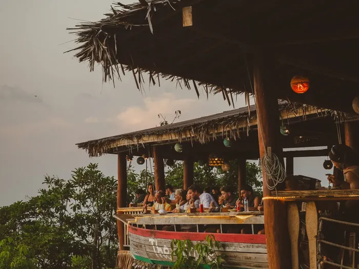 Restauracja pod strzechą o zmierzchu, wspólny stół nad koronami drzew